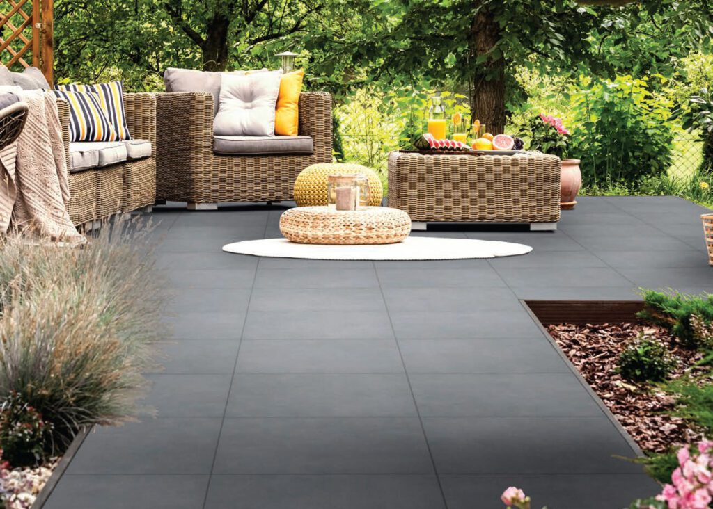 dark gray patio with a chair and ottoman in a backyard
